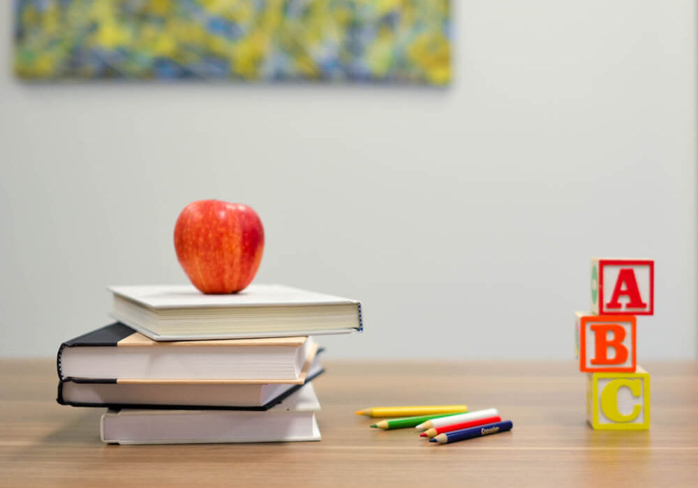  A teacher’s desk with an apple, books, colored pencils, and blocks