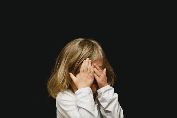 Young girl covering her face with both hands